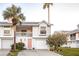 Charming two-story home boasts a pink door, garage, palm trees, and well-maintained landscaping at 112 Sun Isle Cir # 112, Treasure Island, FL 33706