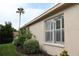 The exterior side view features windows with white frames, green bushes, landscaping and a tall palm tree at 11323 Highlander Ct, Spring Hill, FL 34609