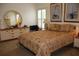 The bedroom features a queen bed, round mirror, and matching dressers with neutral tones and floral accents at 11323 Highlander Ct, Spring Hill, FL 34609