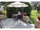 A patio with a stone enclosure includes a table, chairs, an umbrella, and green bushes around the edge at 11323 Highlander Ct, Spring Hill, FL 34609
