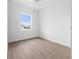 Empty bedroom with hardwood-style floors, ceiling fan, and a large window with neighborhood view at 115 White Marsh Ln, Rotonda West, FL 33947