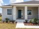 Close up of the front porch with a blue front door and meticulously landscaped surroundings at 115 White Marsh Ln, Rotonda West, FL 33947