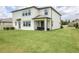 Spacious backyard featuring a well-manicured lawn, covered patio with seating, and a pristine exterior at 12189 Nouveau Ave, Spring Hill, FL 34610
