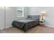 Neutral bedroom with grey bed, white walls, carpet flooring, and modern lamp at 12189 Nouveau Ave, Spring Hill, FL 34610
