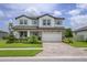 Charming two-story home featuring a brick-accented facade, paver driveway, manicured lawn, and bright blue window shutters at 12189 Nouveau Ave, Spring Hill, FL 34610