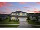 Two-story home featuring a brick driveway, attached two-car garage, manicured lawn and colorful landscaping at 12189 Nouveau Ave, Spring Hill, FL 34610
