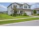 Beautiful two-story home featuring a brick-accented facade, paver driveway, manicured lawn, and bright blue window shutters at 12189 Nouveau Ave, Spring Hill, FL 34610