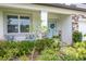 Charming front porch with seating, lush landscaping, and a light blue front door with a decorative wreath at 12189 Nouveau Ave, Spring Hill, FL 34610