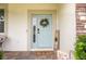 Inviting entryway with a light blue front door, decorative wreath, and stylish welcome sign on a brick-paver porch at 12189 Nouveau Ave, Spring Hill, FL 34610