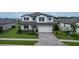 Elegant two-story home with a pristine lawn, a stone-accented facade, and a paver driveway at 12189 Nouveau Ave, Spring Hill, FL 34610