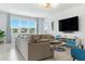 Bright living room featuring a large sectional sofa, large windows, and a modern entertainment center at 12189 Nouveau Ave, Spring Hill, FL 34610