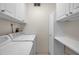 Functional laundry room with upper cabinets and storage shelf provides practicality and organization at 1269 Drew St, Clearwater, FL 33755