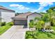 Charming home exterior with gray siding, a gray garage door, and tropical plants at 12838 Wildflower Meadow Dr, Riverview, FL 33579
