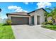 Charming front exterior with gray siding, a gray garage door, green grass, and a sidewalk at 12838 Wildflower Meadow Dr, Riverview, FL 33579