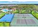 Aerial view featuring community tennis and basketball courts surrounded by lush green spaces and trees at 12838 Wildflower Meadow Dr, Riverview, FL 33579