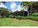 Lovely backyard featuring a screened patio, mature landscaping, and verdant green grass at 13851 Lake Point Dr, Clearwater, FL 33762