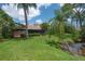 Manicured backyard with lush lawn, mature palm trees, and screened-in patio, perfect for outdoor living at 13851 Lake Point Dr, Clearwater, FL 33762
