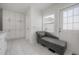 Bathroom features a white chaise lounge, white cabinets, white door, and a window that brings in natural light at 13851 Lake Point Dr, Clearwater, FL 33762