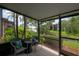 Enclosed lanai with wicker furniture offering scenic views of lush landscaping and serene water at 13851 Lake Point Dr, Clearwater, FL 33762