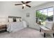 Cozy bedroom featuring a neutral color palette, a ceiling fan, and a large window with green views at 19003 Cedar Ln, Lutz, FL 33548