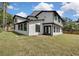 Rear exterior view of a home featuring black trim, stucco facade, and ample yard space at 19003 Cedar Ln, Lutz, FL 33548