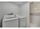Practical laundry room featuring modern washer and dryer units, next to a fully tiled bathroom at 19003 Cedar Ln, Lutz, FL 33548