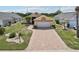 Charming single-story home featuring a brick paver driveway and well-manicured lawn, surrounded by lush landscaping at 1901 E Del Webb Blvd, Sun City Center, FL 33573