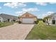 Single-Gathering home featuring a beautiful brick driveway and a well-maintained lawn with shrubs and trees at 1901 E Del Webb Blvd, Sun City Center, FL 33573