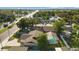 Bird's-eye view of a home with a screened-in pool amidst a neighborhood with lush trees and roadway at 2233 Curlew Rd, Dunedin, FL 34698