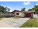 Charming single-story home featuring red accents, an attached garage, and a concrete driveway at 2233 Curlew Rd, Dunedin, FL 34698