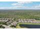 Aerial view of a community featuring a lake, mature trees, and well-maintained homes under a partly cloudy sky at 2427 Nottingham Greens Dr, Sun City Center, FL 33573
