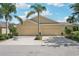 Beige two-car garage home exterior features a driveway and manicured landscaping at 2427 Nottingham Greens Dr, Sun City Center, FL 33573