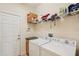 Functional laundry room with washer, dryer and overhead shelving storage at 2427 Nottingham Greens Dr, Sun City Center, FL 33573