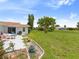 Spacious backyard with a patio, white house, green lawn, and beautiful landscaping, perfect for outdoor entertaining and relaxation at 2436 Nuremberg Blvd, Punta Gorda, FL 33983