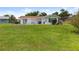 Expansive backyard view of a white house with a red roof, patio area, and lush green lawn at 2436 Nuremberg Blvd, Punta Gorda, FL 33983
