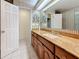 A well-lit bathroom featuring wood cabinets with granite countertops and a large mirror at 307 Fern Cliff Ave, Temple Terrace, FL 33617