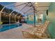 Inviting screened-in pool area with lounge chairs and dining set, illuminated by string lights at 316 Cedar Ln, Largo, FL 33770