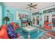 Comfortable sun room with ample seating, TV, ceiling fan, and bright blue accent walls and furniture at 316 Cedar Ln, Largo, FL 33770