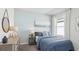 Cozy bedroom featuring a matching blue bedspread, lamps, a pier painting, and a window with white curtains at 35950 Sunflower Hill Dr, Zephyrhills, FL 33541