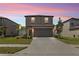Two-story home with a two-car garage surrounded by lawn and minimal landscaping at dusk at 36412 Garden Wall Way, Zephyrhills, FL 33541