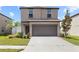 Two-story home with a two-car garage featuring manicured landscaping and a driveway at 36412 Garden Wall Way, Zephyrhills, FL 33541