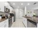 Modern kitchen with stainless steel appliances, white cabinetry and stone countertops at 36412 Garden Wall Way, Zephyrhills, FL 33541