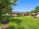 Backyard view of a well-maintained home with lush green lawn, mature trees, landscaping, and a covered porch at 3944 49Th S Ave, St Petersburg, FL 33711