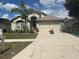 Inviting single-story home with a red front door, a two-car garage, and a lush front yard with mature landscaping at 4436 Horseshoe Pick Ln, Valrico, FL 33594