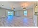 Open living room with gray wood-look floors and sliding glass doors to backyard at 5046 Gato Del Sol Cir, Wesley Chapel, FL 33544