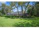 Backyard with a screened-in porch and mature trees bordering lush green lawn and manicured bushes at 511 Duque Rd, Lutz, FL 33549