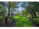 Well-maintained backyard featuring a shed, lush lawn, manicured landscaping, and mature trees at 511 Duque Rd, Lutz, FL 33549