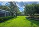 Backyard featuring a screen porch and a lush green lawn framed by mature trees and manicured hedges at 511 Duque Rd, Lutz, FL 33549