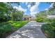 Charming home featuring a manicured lawn, mature landscaping, and a long driveway leading to a two-car garage at 511 Duque Rd, Lutz, FL 33549