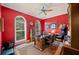 Inviting home office with wood floors, red walls and large arched windows with plantation shutters at 511 Duque Rd, Lutz, FL 33549